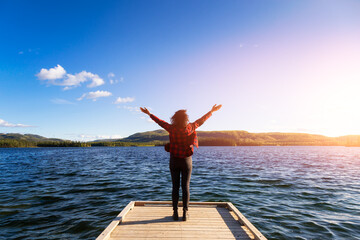 Wall Mural - Adventurous Girl on a Wooden Quay at Twin Lakes Campground during a sunny summer. Sunset Colors. North of Whitehorse, Yukon, Canada. Concept: travel, adventure, freedom