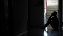 Silhouette Of A Sad Man Sitting In The Dark Leaning Against The Wall In Old Condo, Domestic Violence, Family Problems, Stress, Violence, The Concept Of Depression And Suicide