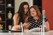© Nexa - adult daughter and mother fiddling with cellphone in the kitchen