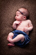 © IdeaBug, Inc. - Newborn Baby Girl Sleeping Peacefully on Brown Blanket, Wearing Headband