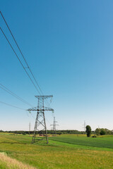 meadow and power line against the blue sky