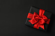 © Atlas - Gift box with red bow on black background
