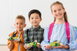 © LIGHTFIELD STUDIOS - Selective focus of multiethnic pupils holding robots and looking at camera in stem school