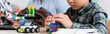 © LIGHTFIELD STUDIOS - Panoramic crop of schoolboy with building blocks modeling robot in stem school