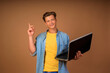 © Daria - modern remote work. portrait of a young guy with a laptop in his hands on a beige background