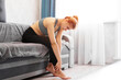© brillianata - Woman sitting on sofa holds her foot injury, feeling pain. Health care and medical concept.