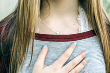 Teenage Girl With Long Hair - Hand To Her Chest And A Silver Heart Necklace