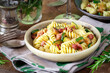 Delicious Italian fusilli pasta with zucchini or courgette and pancetta served in a vintage plate on a dark rustic wooden background