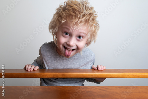 Cuadros en Lienzo Funny boy with blond hair leaned over the banister and looks down