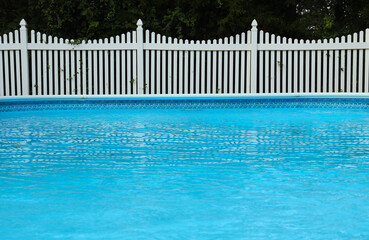  Swimming pool and white vinyl fence in front of trees