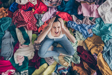 Help. High Angle Above View Photo Of Stressed Yelling Lady Stay Home Spring Cleaning Household Sit Many Clothes Stack Floor Pick Select Look Outfit Nothing To Wear Hands On Head Indoors