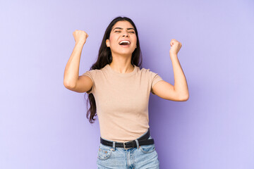 Wall Mural - Young indian woman isolated on purple background raising fist after a victory, winner concept.