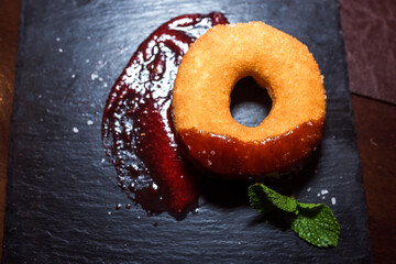 Wall Mural - Fresh donut with red sugar jam on black background