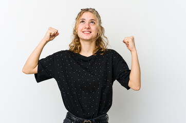 Wall Mural - Young caucasian woman on white backrgound raising fist after a victory, winner concept.