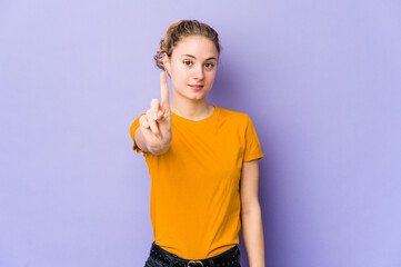 Wall Mural - Young caucasian woman on purple background showing number one with finger.