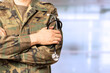 © cunaplus - Cropped shot of an unrecognizable male military doctor standing with his arms folded inside of a hospital during the day