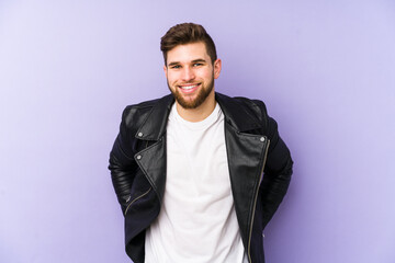 Wall Mural - Young man isolated on purple background happy, smiling and cheerful.