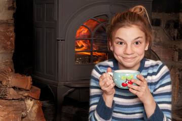 young girl with hot coco in front of woodfire stove 2