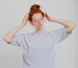© oleg_ermak - Portrait of tender redhead girl wearing her hair in bun with healthy freckled skin, serious or pensive expression. Caucasian woman model with ginger hair posing indoors in oversize shirt