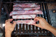 Hands putting ribs on the grill for an Argentinean barbecue asado