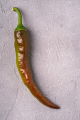 Wall Mural - Hot spicy green and red chili pepper on stone concrete background, top view macro