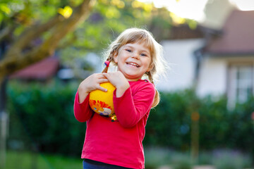 Wall Mural - Little adorable toddler girl playing with ball outdoors. Happy smiling child catching and throwing, laughing and making sports. Active leisure with children and kids.