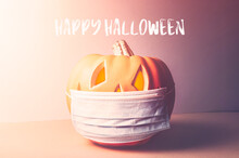 Happy Halloween 2020 Text. New Normal And New Reality Concept. Orange Pumpkin Or Halloween Jack O Lantern In Medical Protective Mask, Halloween And Covid-19 Concept