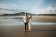 © Leah Flores/Stocksy - Couple Walking on Beach