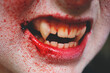 © Natalie JEFFCOTT/Stocksy - Close up of vampire's mouth and teeth splattered with blood