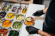 © Sergio Marcos/Stocksy - Anonymous waiter filling a poke bowl with food