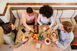 © MyMicrostock/Stocksy - Friends around table with tasty food in cafe