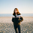 © Jakob Lagerstedt/Stocksy - Beautiful woman in a her forties standing on a beach in a winter jacket