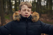 © sally anscombe/Stocksy - Young boy stood in the woods with his eyes closed tight shut