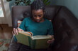 © Gabriel (Gabi) Bucataru/Stocksy - Black girl reading on a couch