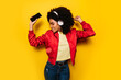 © MyMicrostock/Stocksy - Beautiful afro woman listening to music with white headphones and cellphone