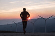 © Hakan & Sophie/Stocksy - man running towards wind generators in the setting sun