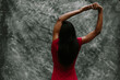 © JImena Roquero/Stocksy - Woman in red stretching her arms over grey background.