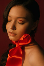 A Closeup Portrait Of An Asian Girl With A Red Belt On Her Neck And A Love-word On Her Eye