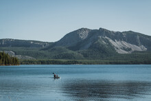 People Kayaking On Lake And Near The Mountains