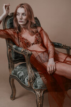 Peachy Girl Portrait In Bra And Transparent Red Dress Sitting In Vintage Chair