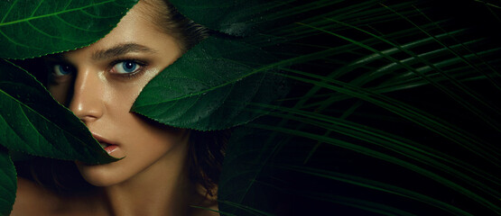 Wall Mural - a beautiful tanned young woman with natural makeup and wet hair stands in the jungle among exotic pl