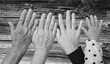 Schwarz-Weißaufnahme von vier Hände im Alter von jeweils 93 Jahren, 63 Jahren, 33 Jahren und 2 Jahren vor einem Hintergrund mit Holzstruktur