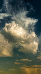 Wall Mural - vertical panoramic view of a dramatic sky with cumulus clouds and warm lighting from below. Artistic creative background