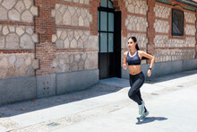 Side View Of Fit Female In Sportswear Running Fast Along Pavement During Training On Sunny Day In City