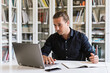 © Galdric Penarroja/ADDICTIVE STOCK - Focused businessman in formal shirt sitting at table while doing paperwork and typing on notebook in bright workspace