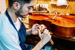 © Javier Ballester/ADDICTIVE STOCK - Side view of skilled young male artisan with knife carving wooden violin bridge while creating string instrument in workshop