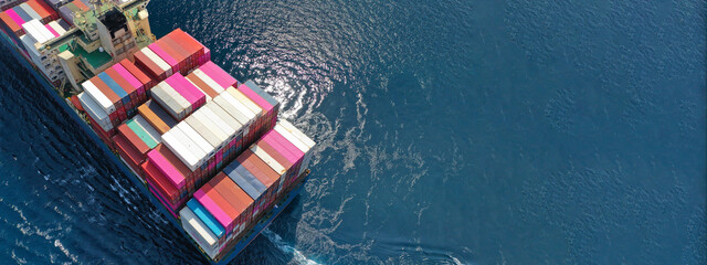 Aerial drone panoramic ultra wide photo of industrial container tanker ship loaded with colourful truck size containers cruising open ocean deep blue sea