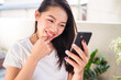 © Juan Alberto Ruiz/ADDICTIVE STOCK - Asian female browsing dating app on smartphone and choosing boyfriend while resting on terrace