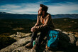 © Lucia Romero/ADDICTIVE STOCK - Optimistic man resting sitting on stones with eyes closed near backpack while enjoying the moment in Puerto de la Morcuera mountains on cloudy day in Spain