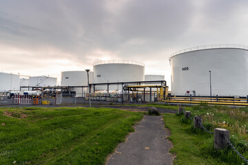 White oil storage tanks in a industrial area at sunset